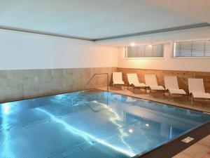 a swimming pool with white chairs in a room at Attractive apartment in Wald am Arlberg in Wald am Arlberg