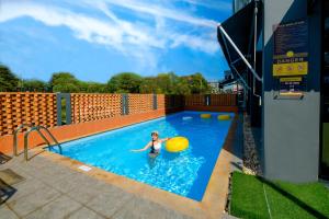 a woman in a swimming pool with a frisbee at Sleep Mai Chiang Mai Airport Lifestyle Hotel - SHA Plus in Chiang Mai