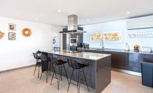 a kitchen with a large island with bar stools at Villa BuenaVista Hills - Sea View - Infinity Pool - Parking - Grill in Málaga