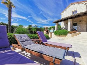 un patio con 2 sedie a sdraio e una casa di Family Villa Blum a Dobrinj
