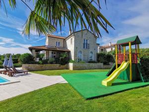 un parco giochi di fronte a una casa con scivolo di Family Villa Blum a Dobrinj