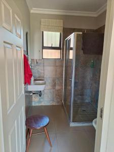 a bathroom with a shower and a sink and a stool at Mill Cottages - Rosetta in Rosetta