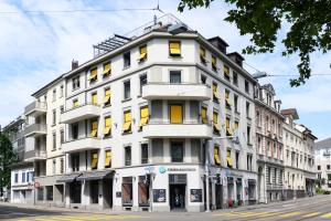a white building with yellow windows on a city street at VISIONAPARTMENTS Brandschenkestrasse - contactless check-in in Zürich