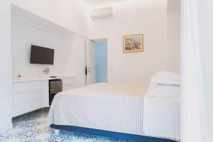 a white bedroom with a bed and a tv at B&B L'Agapanto in Capri