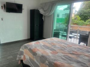 ein Schlafzimmer mit Bett und ein Balkon mit Fernseher in der Unterkunft Renta casa nueva Oaxtepec in Oaxtepec