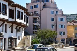 two cars parked in front of a tall pink building at Helen & Friends 3 bedrooms in Balchik
