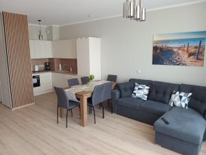 a kitchen and a living room with a table and a couch at Apartament rodzinny 47, 150 m od plaży, basen, plac zabaw, darmowy parking! in Sianozety