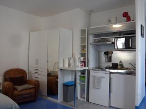 une cuisine avec des armoires blanches et une chaise dans une pièce dans l'établissement Studio 27m2 centre-ville, à Bourges