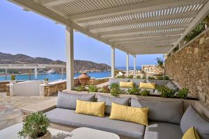 a patio with a couch under a pergola at Ios Palace Hotel & Spa in Mylopotas