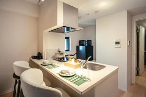 a kitchen with a sink and a counter with chairs at Tanimachi Namba East43 in Osaka