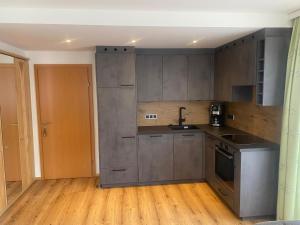 kuchnia z szarymi szafkami i drewnianą podłogą w obiekcie Sixtl, Landhaus w mieście Bad Hofgastein