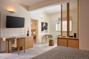 a bedroom with a bed and a desk with a television at Ios Palace Hotel & Spa in Mylopotas