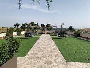 a garden with benches and a pathway with grass at Hotel Sercotel Cuatro Postes in Avila
