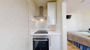 a small white kitchen with a sink and a bed at Studio 20 Ash in London +17 photos