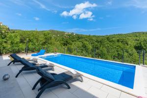 a swimming pool with two lounge chairs and a swimming pool at Villa Manola by Briskva in Labin