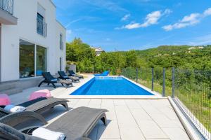 a swimming pool with chaise lounge chairs next to a house at Villa Manola by Briskva in Labin +35 photos