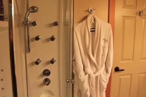 una bata blanca colgada en una puerta junto a una ducha en Windborne Bed & Breakfast, en Castlegar