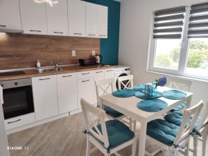 a kitchen with white cabinets and a table and chairs at Вила TIMeS in Kiten