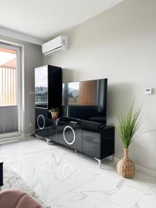 a living room with a black entertainment center with a television at Laguna Beskidów Resort - Apartament A74 in Zarzecze +37 photos