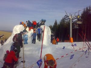 eine Gruppe von Menschen auf einem Skilift im Schnee in der Unterkunft Pension Medvidek in Loučná pod Klínovcem