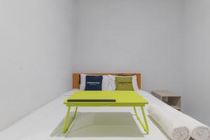 a bed with a green table with pillows on it at UrbanView Hotel 3m Syariah in Bandung