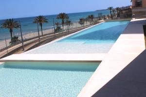een zwembad naast een strand met palmbomen bij Luxury penthouse with private pool in El Campello