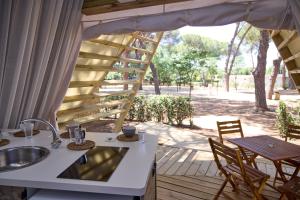 a porch with a sink and a table and chairs at Costa D'Argento - Camping Village Club Capalbio in Capalbio