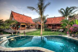 a villa with a swimming pool in front of a house at The Kampung in Amed