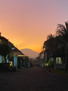 an empty street at sunset with a mountain in the background at Villa Plumeria A3 in Jember