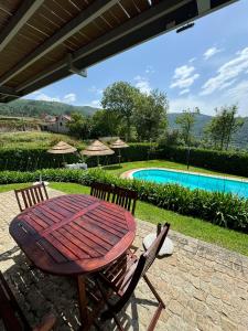 una mesa de madera, 2 sillas y una piscina en Casa das Castanhas - Cinfães, Viseu, en Cinfães