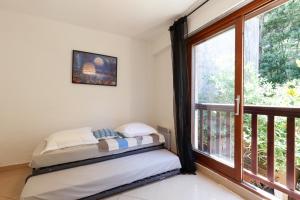two beds in a room with a large window at Jolie Maison Proche Plage in Toulon +21 photos