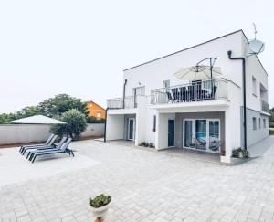 a white house with two chairs and a balcony at Villa Milutin 1 in Vrsi