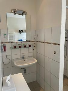 a white bathroom with a sink and a mirror at Hotel Corsten in Heinsberg
