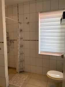 a bathroom with a shower and a toilet with a window at Hotel Corsten in Heinsberg