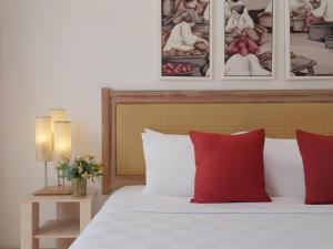 a bedroom with a bed with red pillows and pictures on the wall at Blu-Zea Resort by Double-Six in Seminyak
