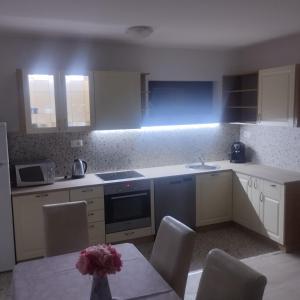 eine Küche mit weißen Schränken und einem Tisch mit Stühlen in der Unterkunft House Daniela in Omišalj