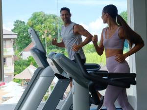 a man and a woman on a treadmill in a gym at Blu-Zea Resort by Double-Six in Seminyak