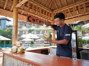 a man standing at a counter holding a drink at Blu-Zea Resort by Double-Six in Seminyak