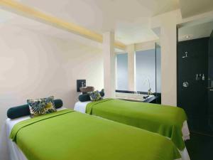 two green beds in a room with a sink at Blu-Zea Resort by Double-Six in Seminyak