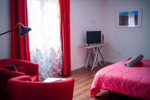 a bedroom with a red bed and a red chair and a window at CASA RURAL GA7COLORES only adult in Montaña Blanca