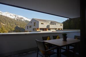 a table and chairs on a balcony with a house at Belvedere - Alpin-Resort Montafon Haus 3 by Pferd auf Wolke in Gargellen