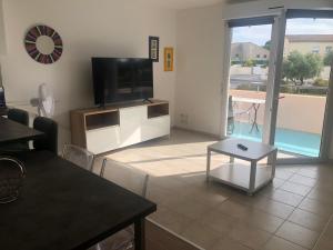 a living room with a flat screen tv and a table at Résidence les Nautiles in Mèze