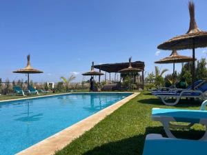 ein Swimmingpool mit Stühlen und Sonnenschirmen in der Unterkunft Villa campagne bouznika in Bouznika + 17 Fotos