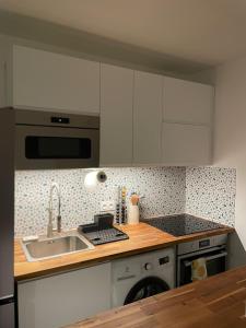 a kitchen with white cabinets and a sink at T2 Suresnes Proche La Défense Paris Parking Fibre in Suresnes +24 photos