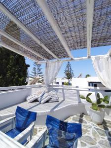 un patio con sedie blu sotto un pergolato bianco di Angelina Greek House a Paroikia