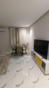 a living room with a table and a large television at New Cairo Serviced Apartment in Cairo