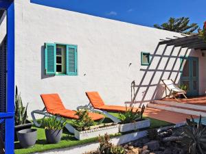 two orange chairs in front of a white house at Casa Belén in Pozo Negro