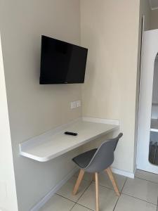 a white desk with a chair and a television on a wall at H2O TROPEA in Tropea