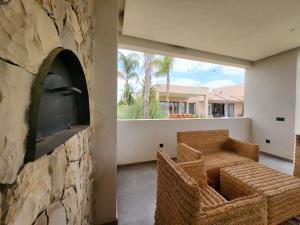 a room with a stone wall with chairs and a tv at Villa Marrakech in Oubadine