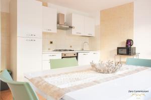 a kitchen with white cabinets and a table with chairs at Villa Vespucci - appartamento di 170mq in Montesilvano